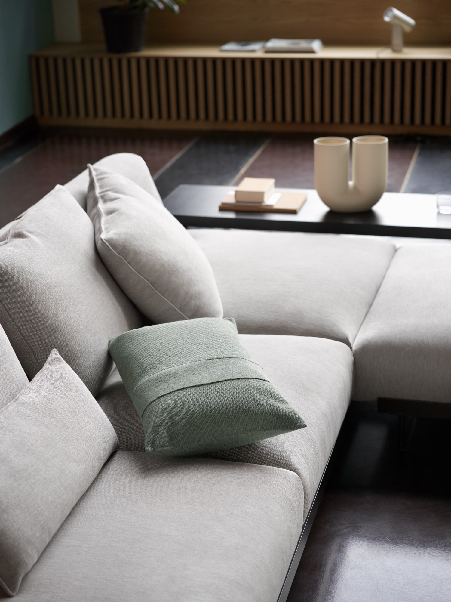In Situ Sofa in Clay 12 with Layer Cushion in sage green and Kink Vase in a minimalist living room setting. In Situ Sofa in Clay 12 with Layer Cushion in sage green and Kink Vase in a minimalist living room setting.