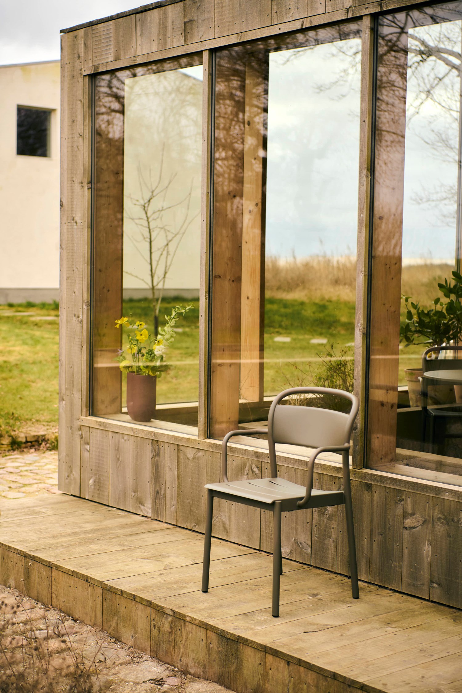 A modern outdoor armchair in a taupe color, positioned in an open outdoor setting for a relaxed, contemporary look. A modern outdoor armchair in a taupe color, positioned in an open outdoor setting for a relaxed, contemporary look.