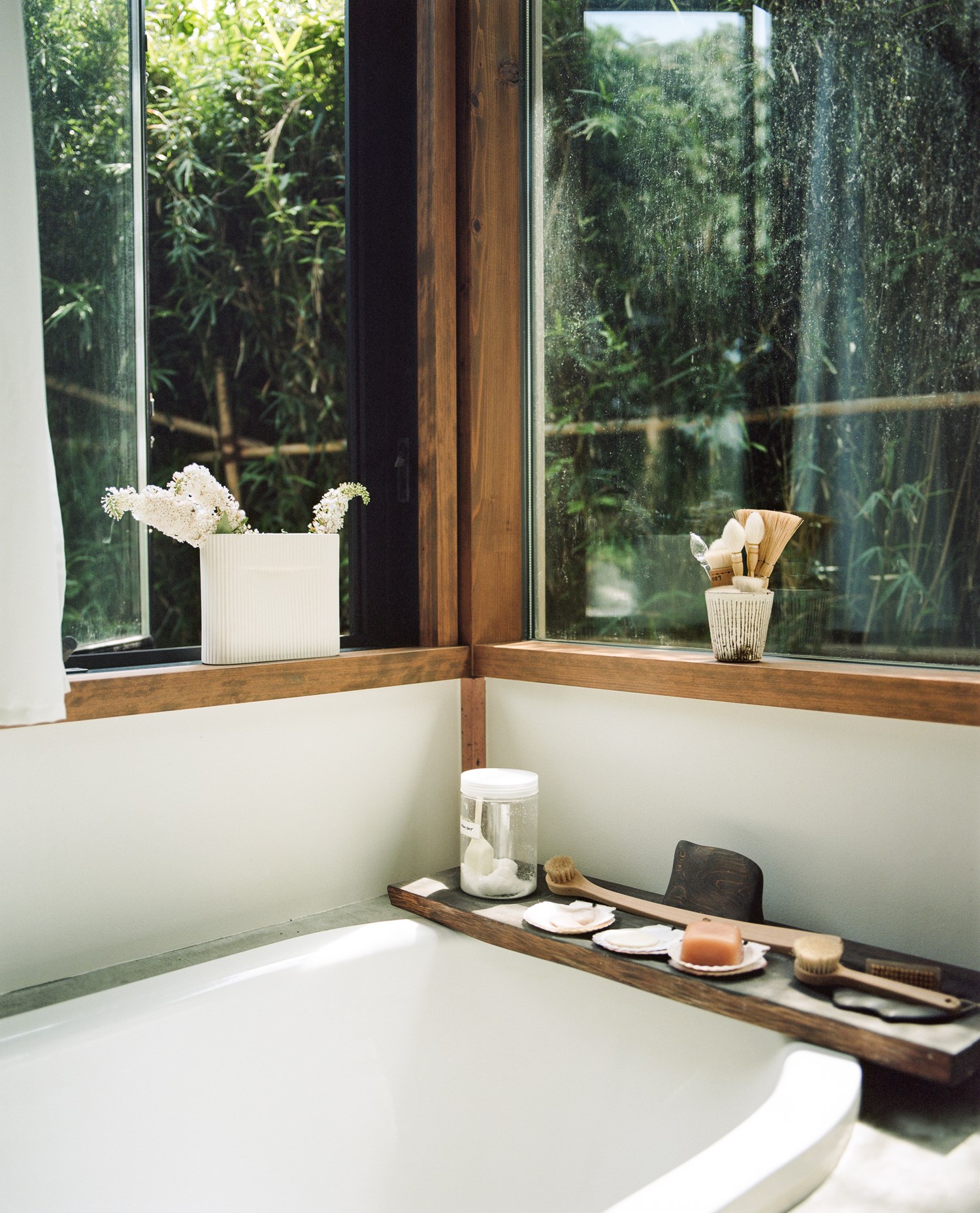 Serene bathroom with a bathtub overlooking a lush garden through a full-length window. Serene bathroom with a bathtub overlooking a lush garden through a full-length window.