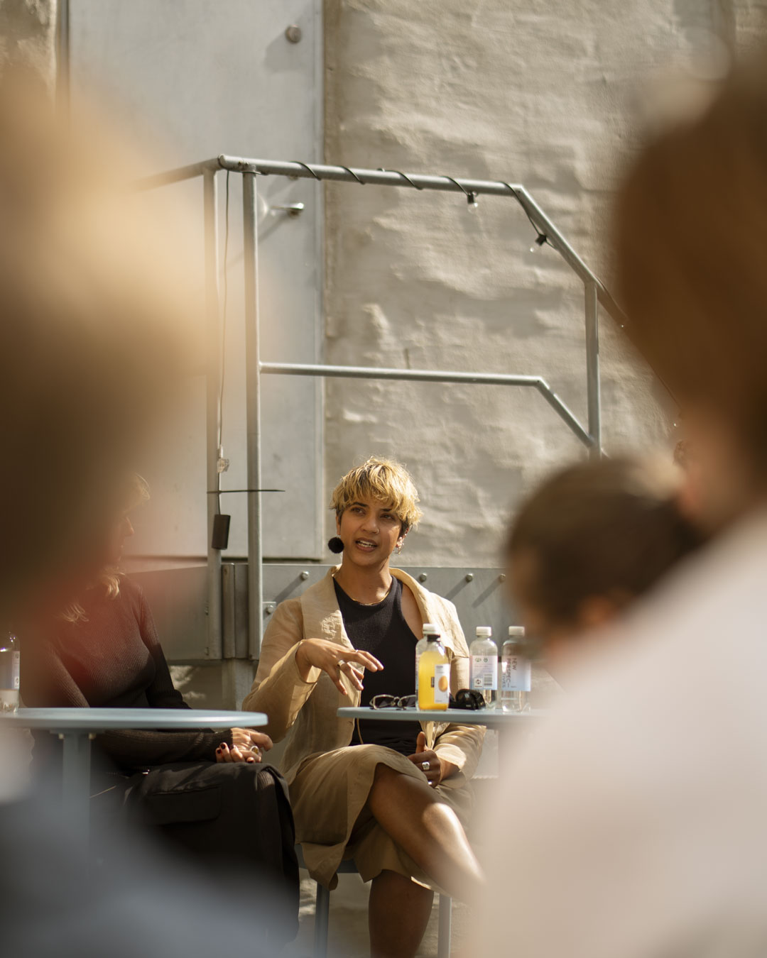 Speakers and audience captured during Muuto’s panel talk, seated in a courtyard setting with soft tones and modern design.
