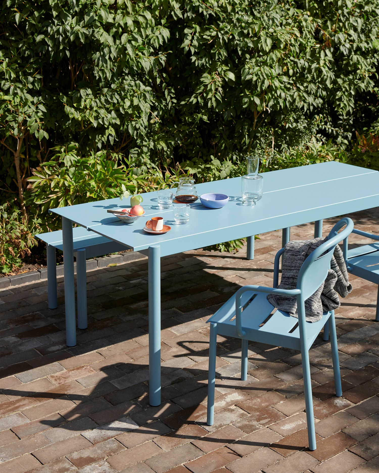 Outdoor setting with Linear Steel Table, chairs, and bench in a minimalist environment Outdoor setting with Linear Steel Table, chairs, and bench in a minimalist environment