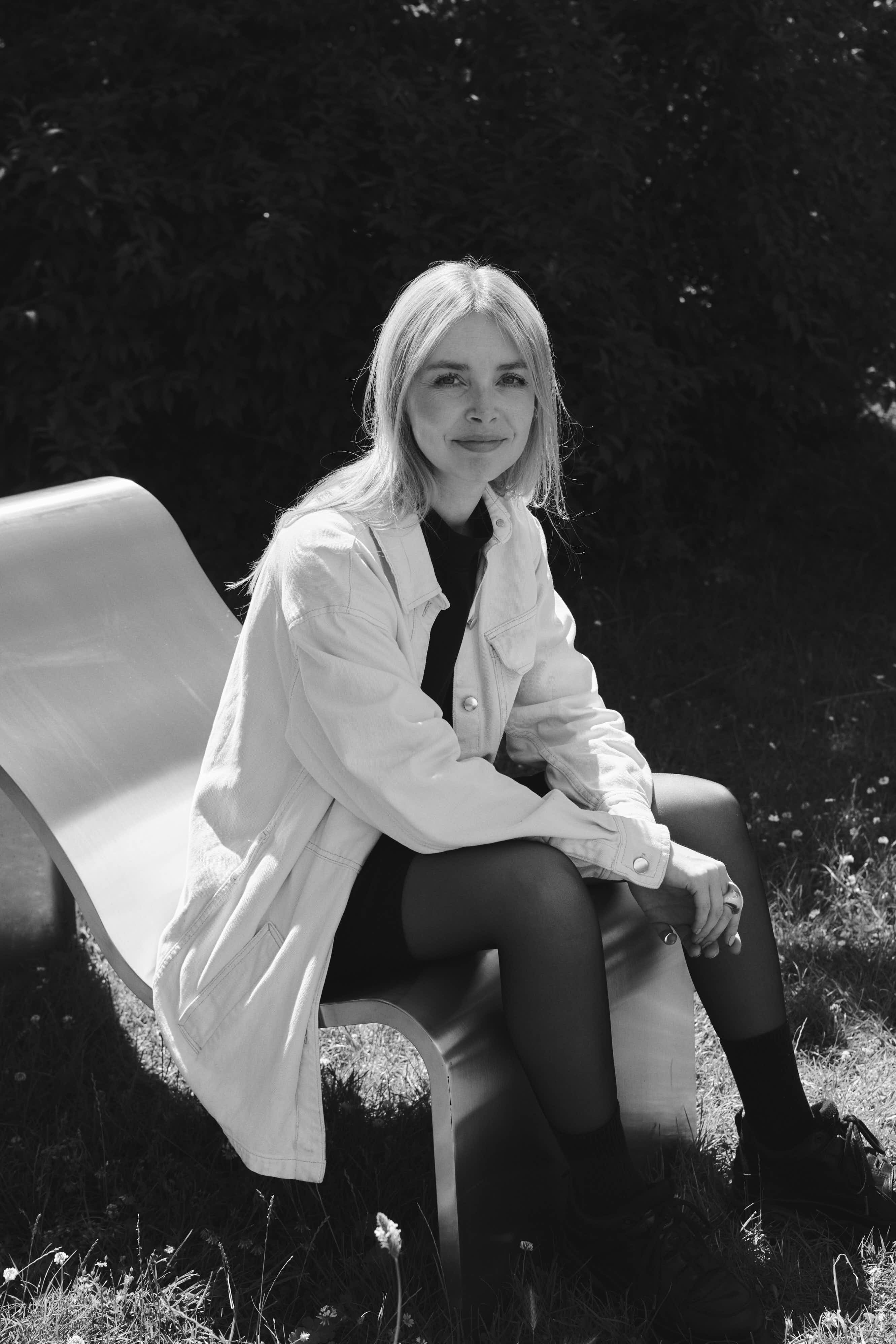 Lise Vester sitting on the Dream View Bench in an outdoor setting, combining the soft, sculptural form of the bench with the calm atmosphere of nature.