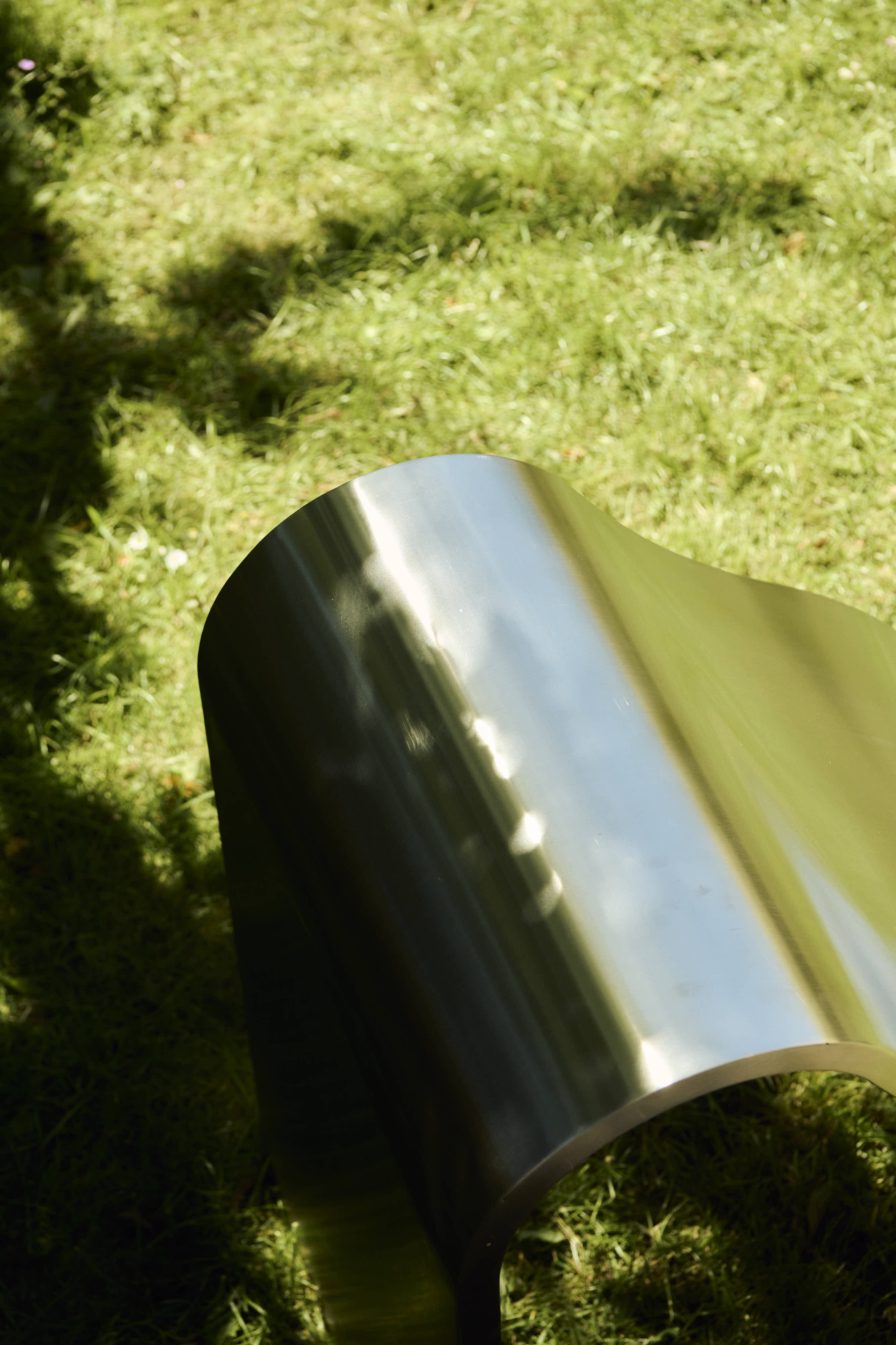 The Dream View Bench by Lise Vester placed on grass in a outdoor environment, highlighting its soft shape and calm presence in the landscape.