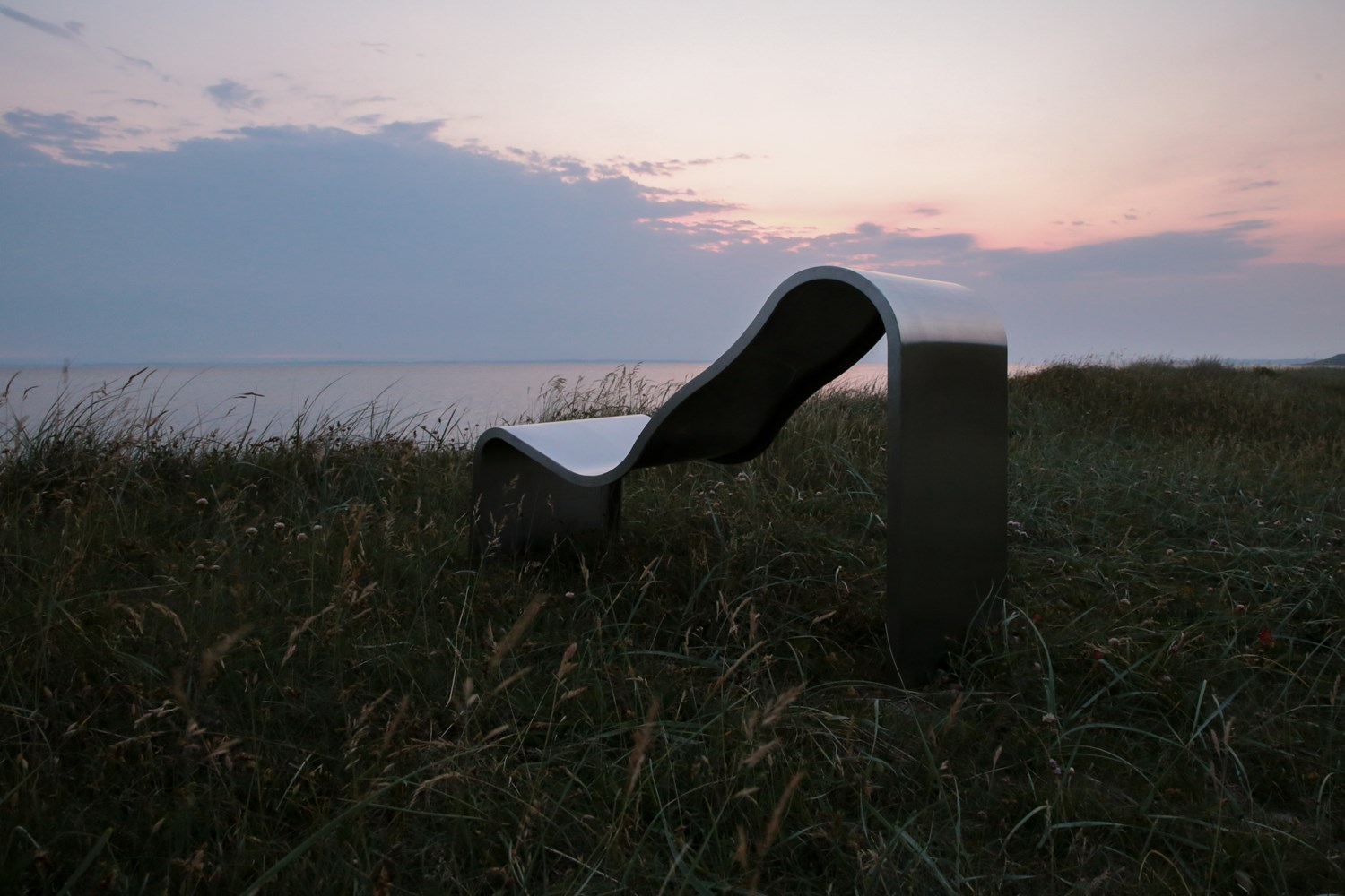 The Dream View Chair is placed outdoors on a green grass field, bathed in the warm glow of the sunset. The Dream View Chair is placed outdoors on a green grass field, bathed in the warm glow of the sunset.