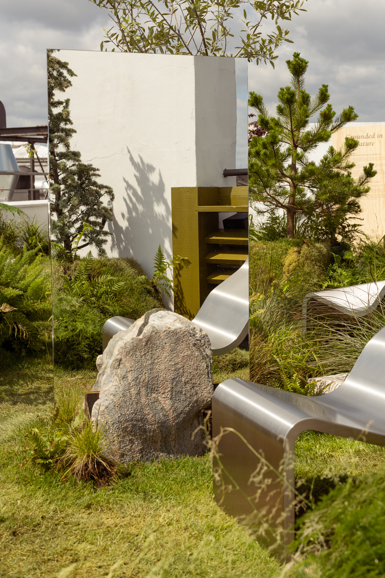 An image of the Dream View Chair placed on a rooftop surrounded by lush green plants and grass, creating a serene and calming atmosphere.
