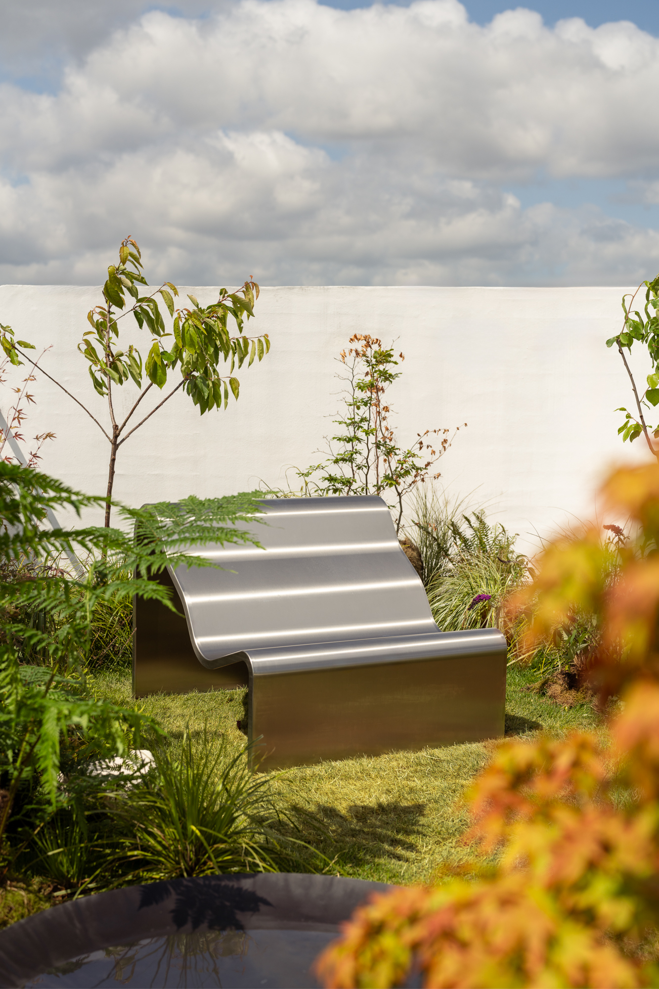 An image of the Dream View Bench placed on a rooftop surrounded by lush green plants and grass, creating a serene and calming atmosphere.