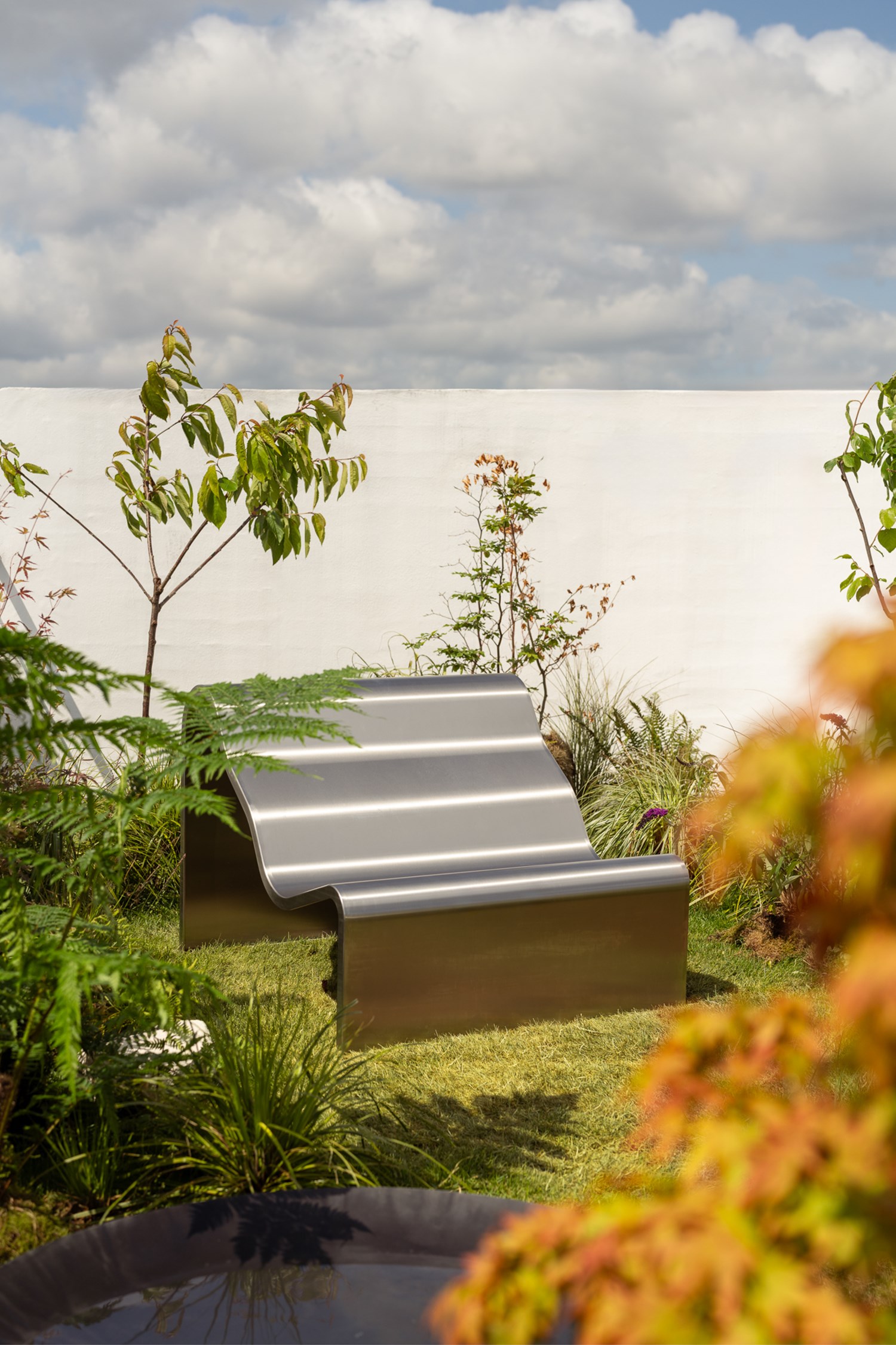 An image of the Dream View Bench placed on a rooftop surrounded by lush green plants and grass, creating a serene and calming atmosphere. An image of the Dream View Bench placed on a rooftop surrounded by lush green plants and grass, creating a serene and calming atmosphere.