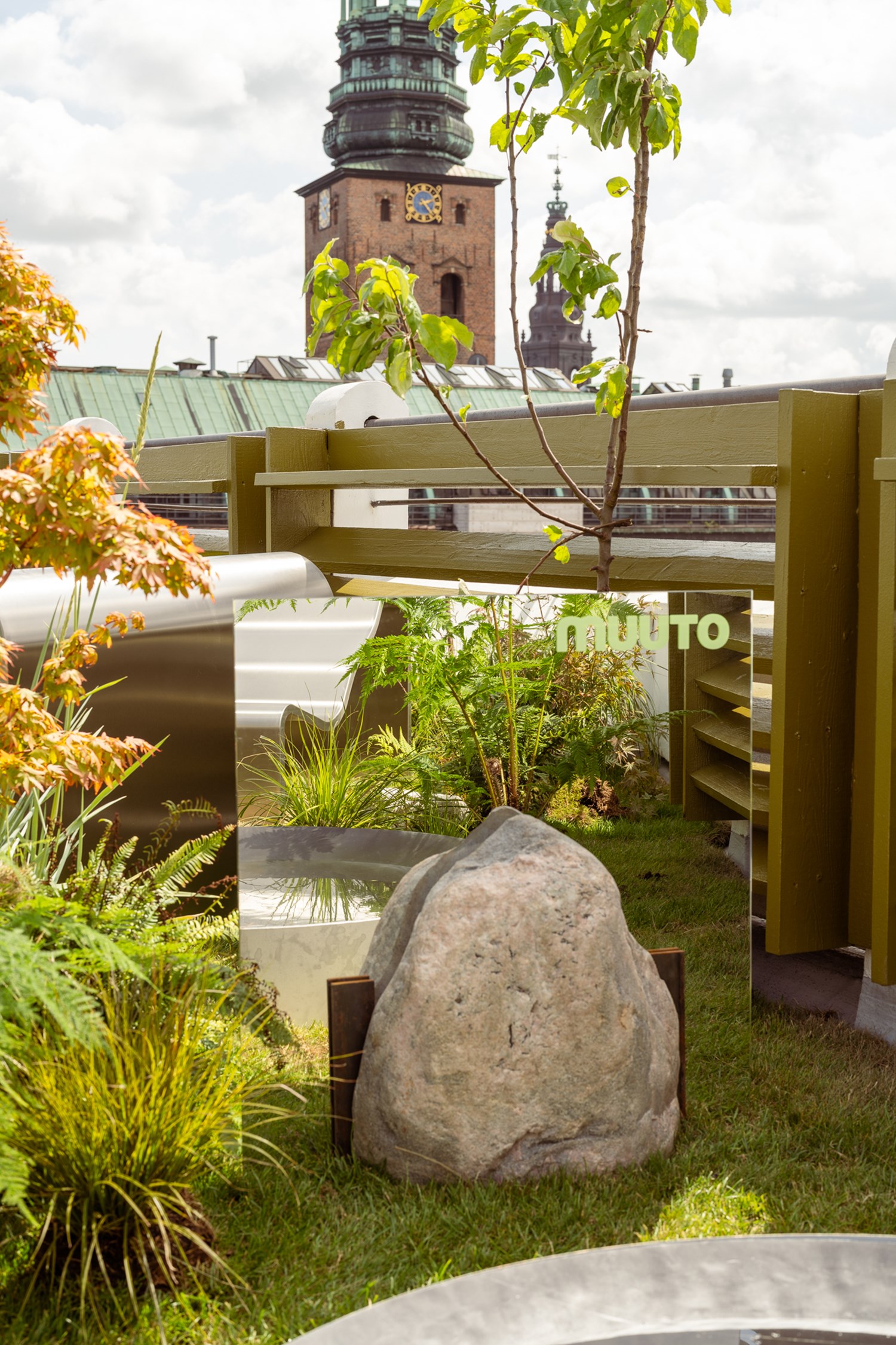 An image of the Dream View Bench placed on a rooftop surrounded by lush green plants and grass, creating a serene and calming atmosphere. An image of the Dream View Bench placed on a rooftop surrounded by lush green plants and grass, creating a serene and calming atmosphere.