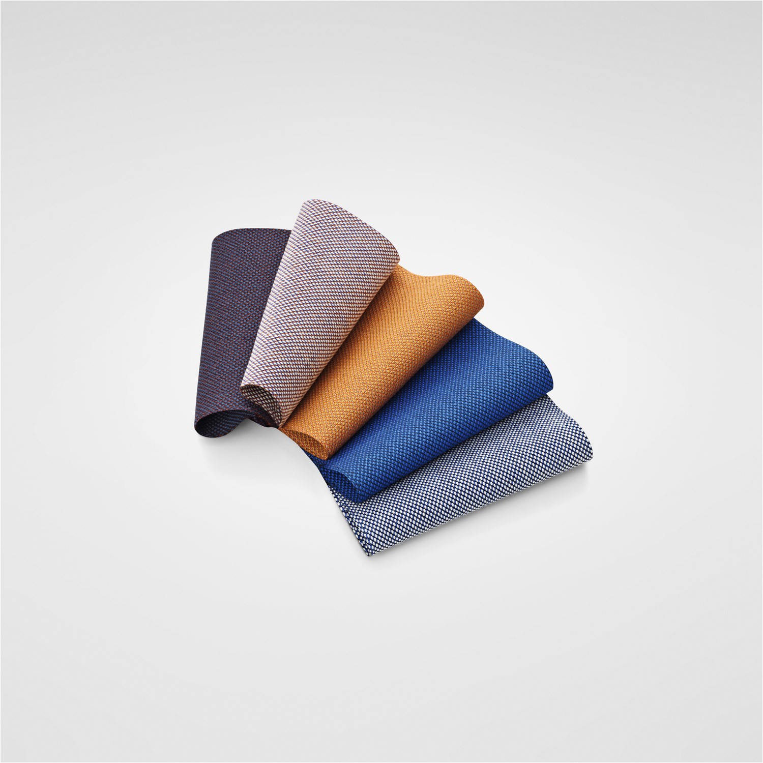 An assortment of fabric swatches. An assortment of fabric swatches neatly displayed, featuring rich shades of blue, red, brown and beige.
