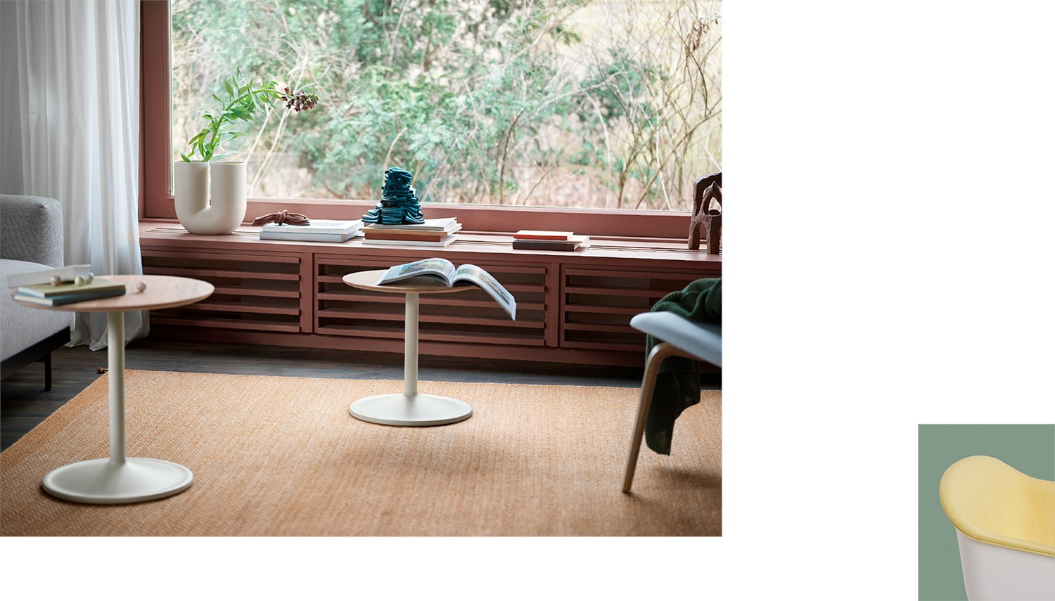 Living room setting with two Soft Side Tables in neutral tones. A large window seat with books, decorative objects, and a Kink vase frames a view of the garden outside. Calm and minimalist atmosphere with warm, muted colors. Living room setting with two Soft Side Tables in neutral tones. A large window seat with books, decorative objects, and a Kink vase frames a view of the garden outside. Calm and minimalist atmosphere with warm, muted colors.